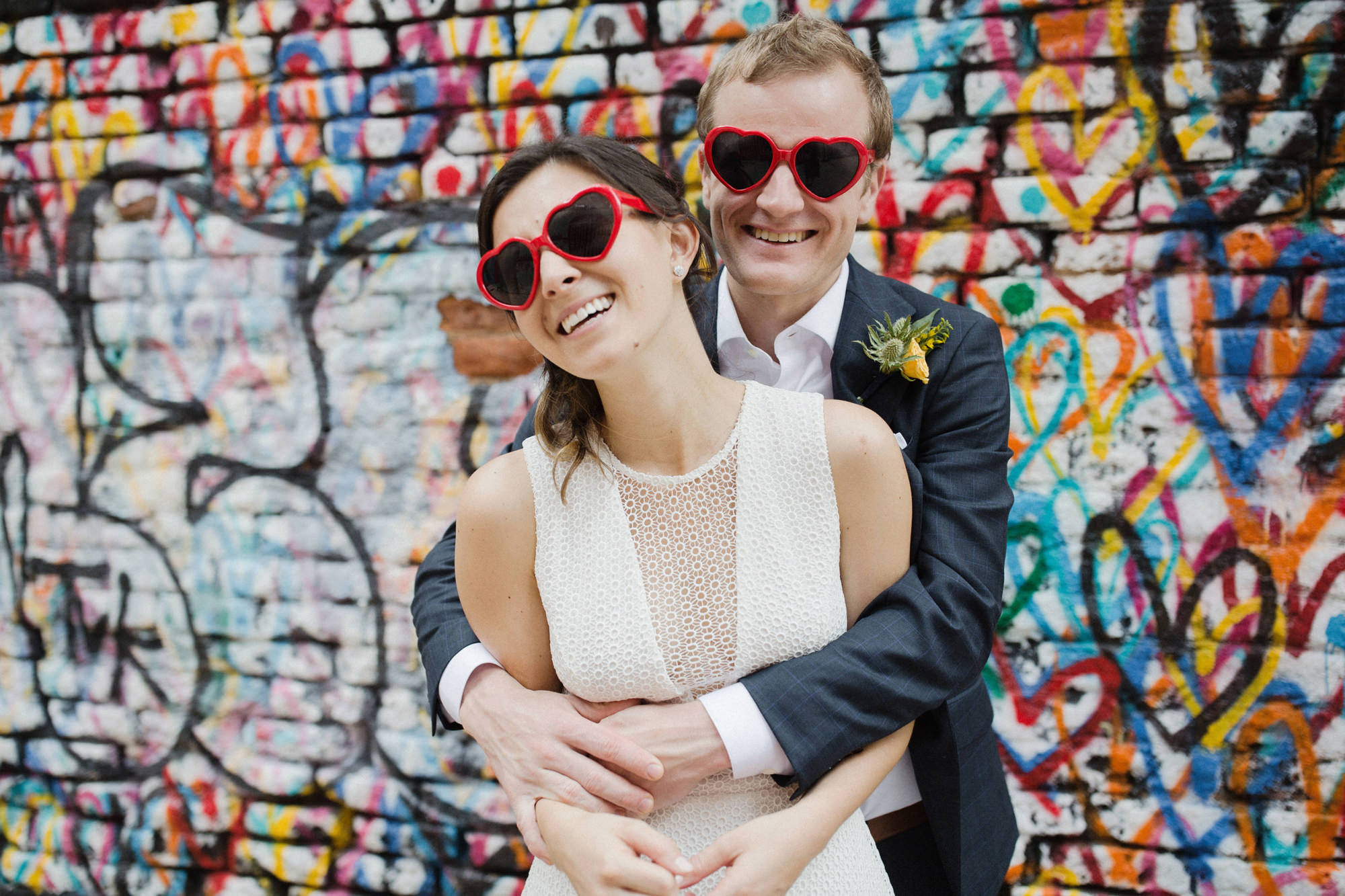 bride and groom wearing love heart sunglasses