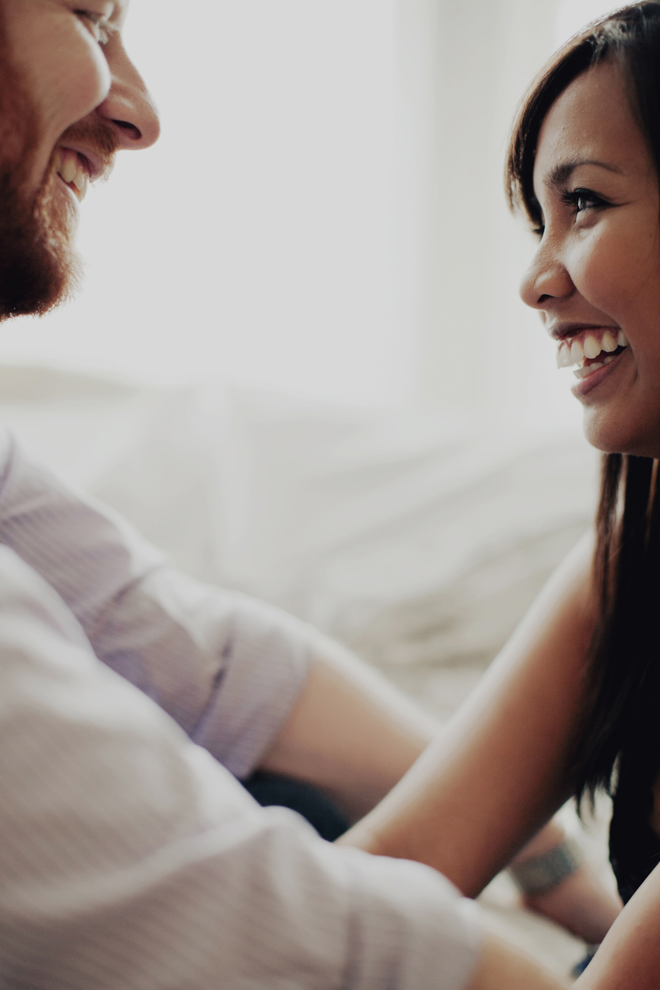 Couple on bed laughing at portrait session