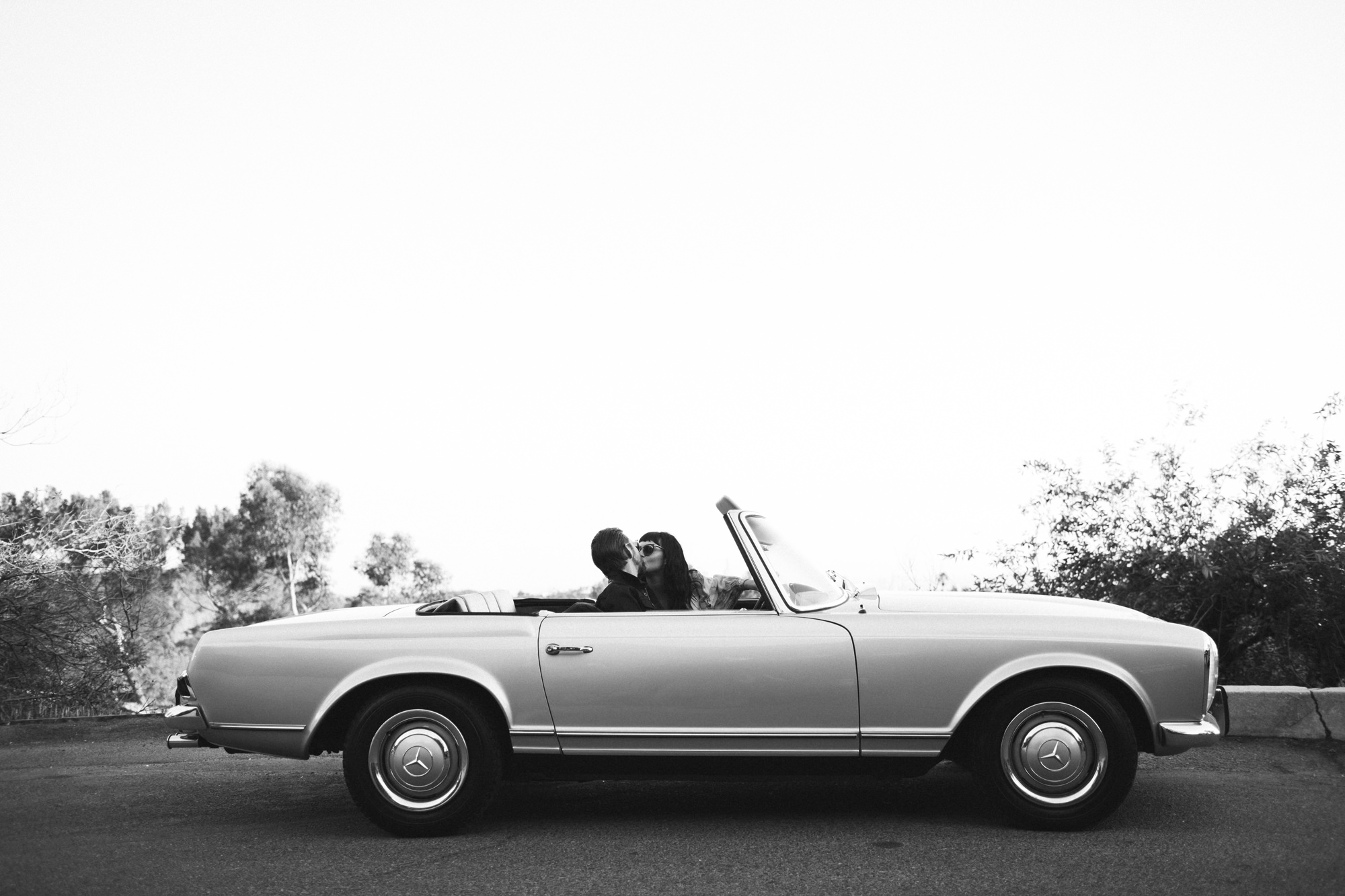 Couple kissing in vintage car at engagement portrait shoot