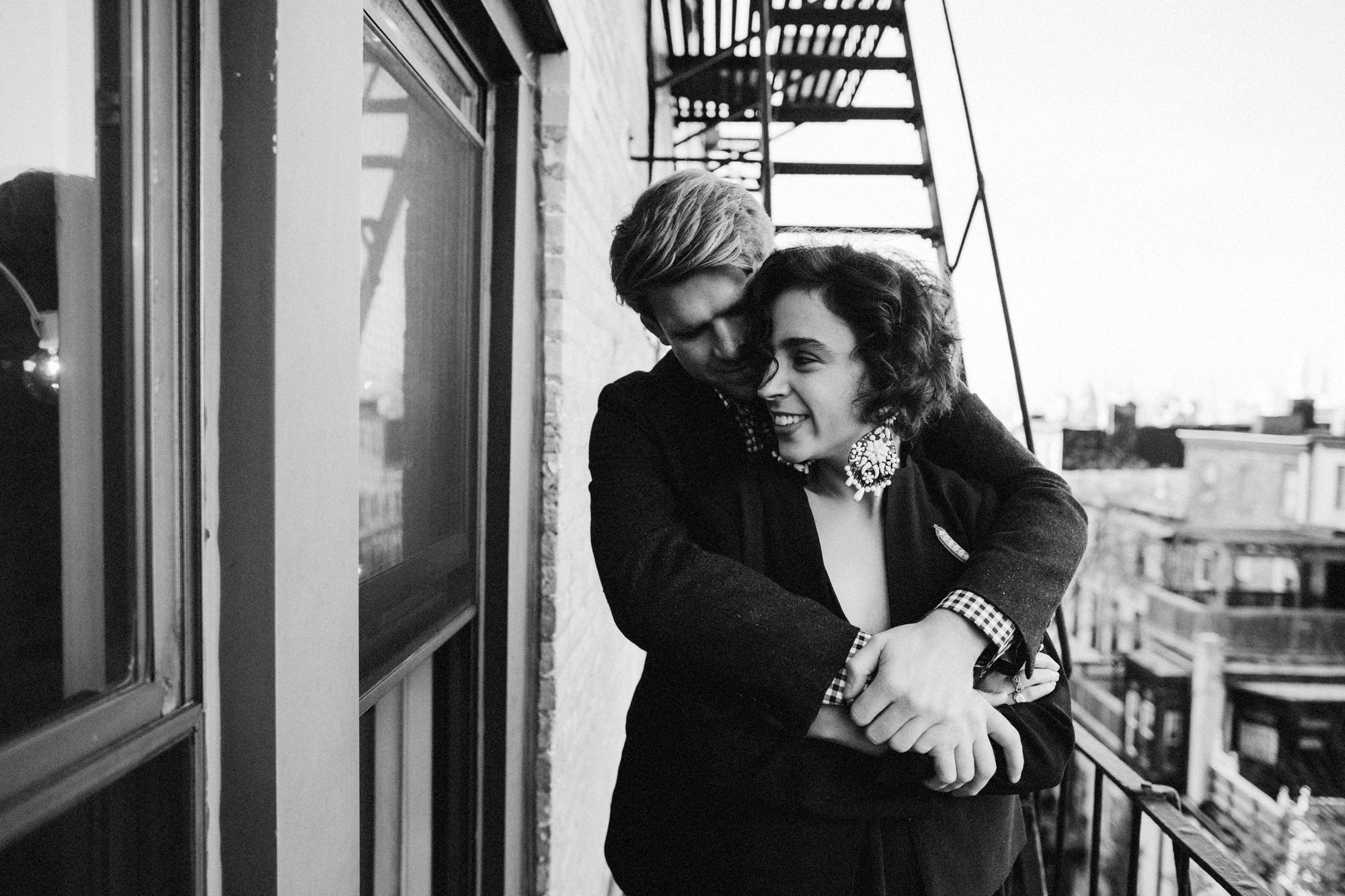 Couple cuddling on fire escape in Brooklyn