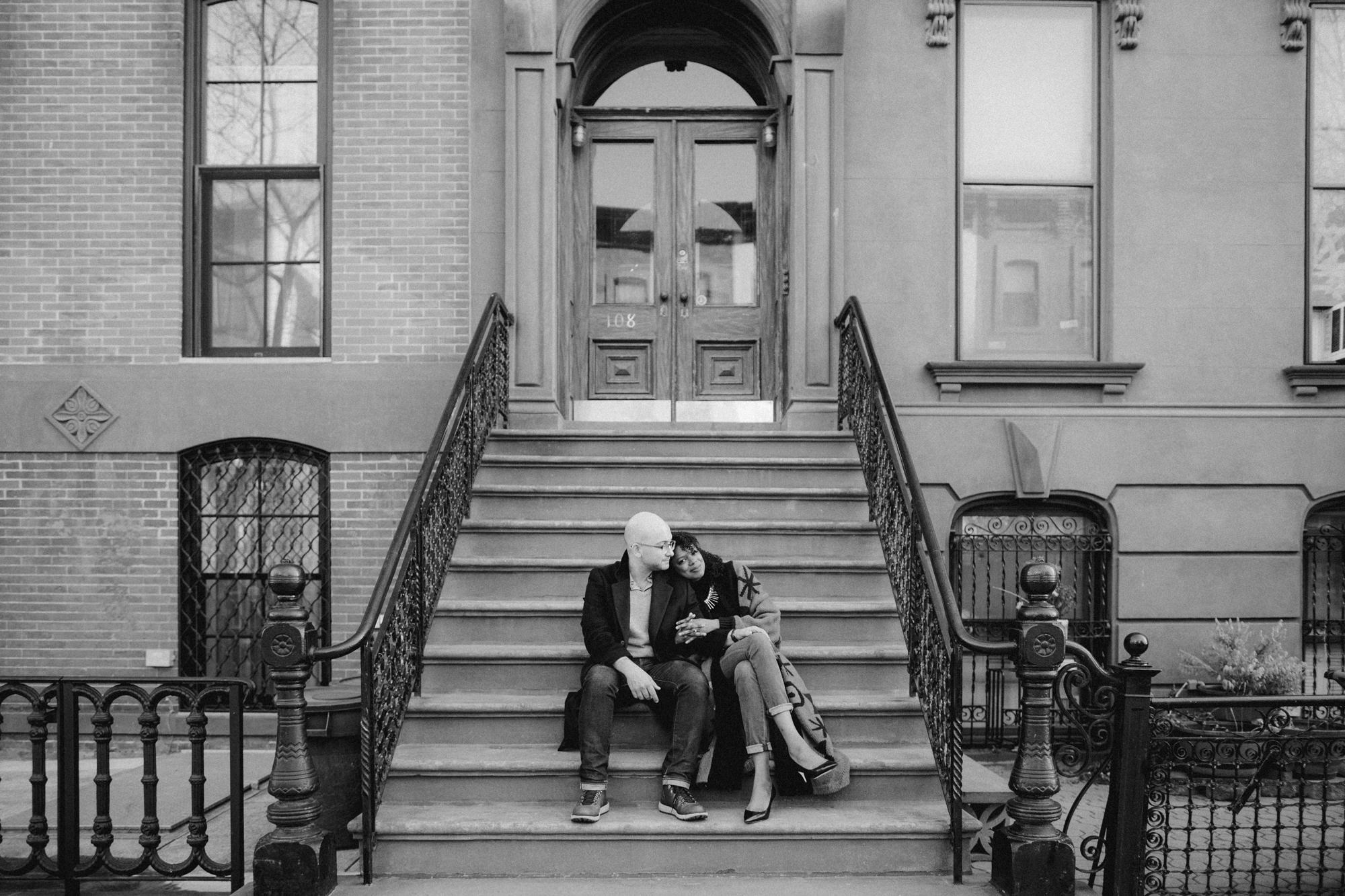 Couple sitting on brownstone stairs in Brooklyn