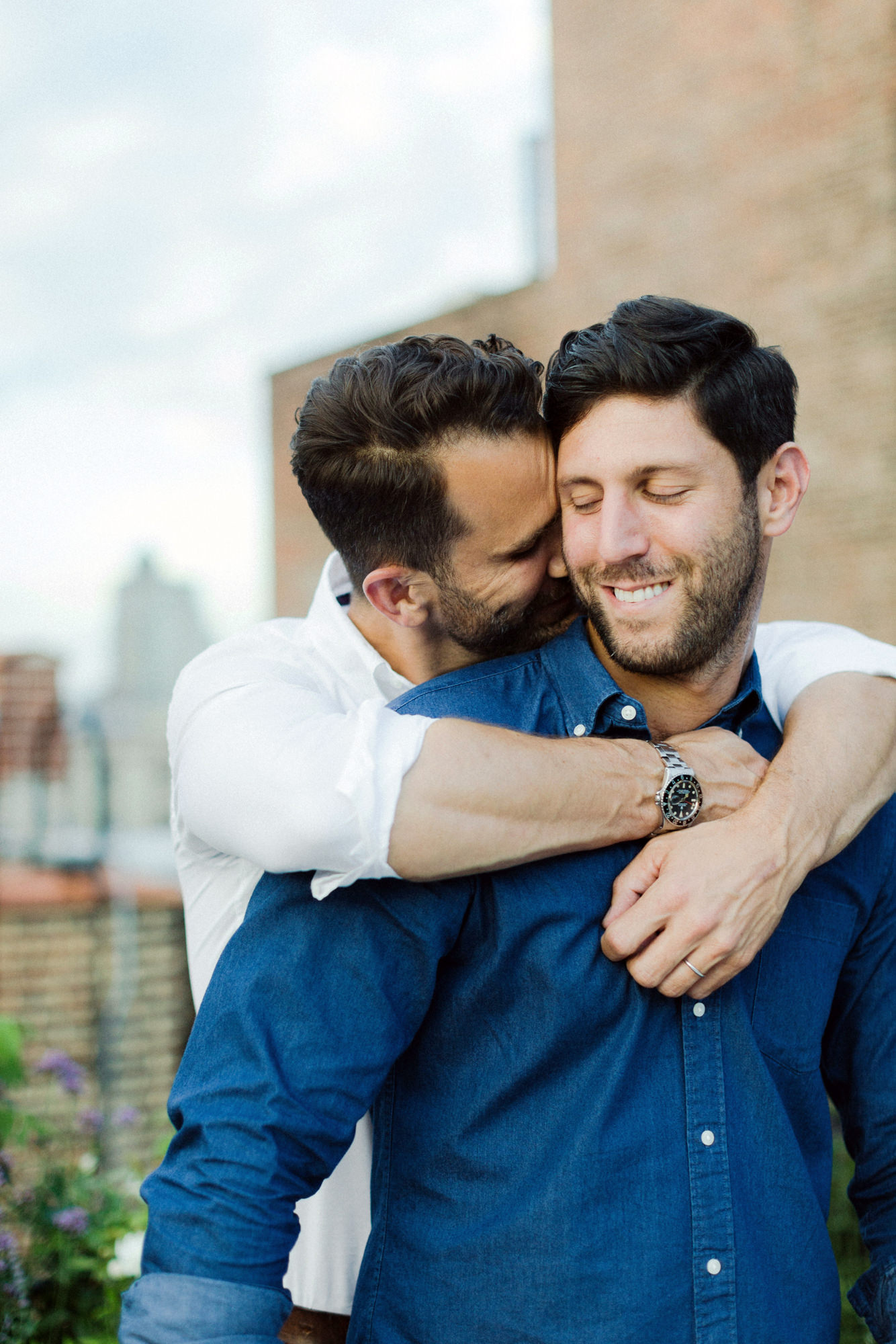 Same sex couple cuddling on rooftop
